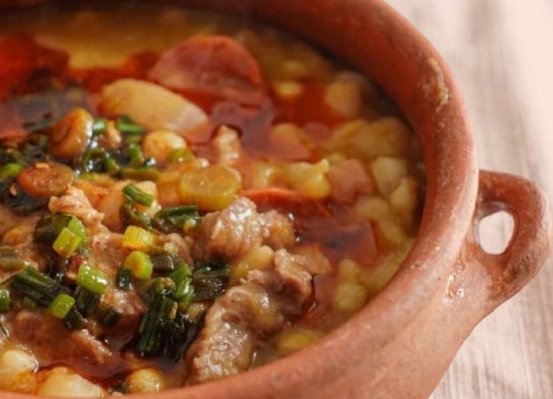 Cazuela de barro con locro casero, choclo, carne y verdeo