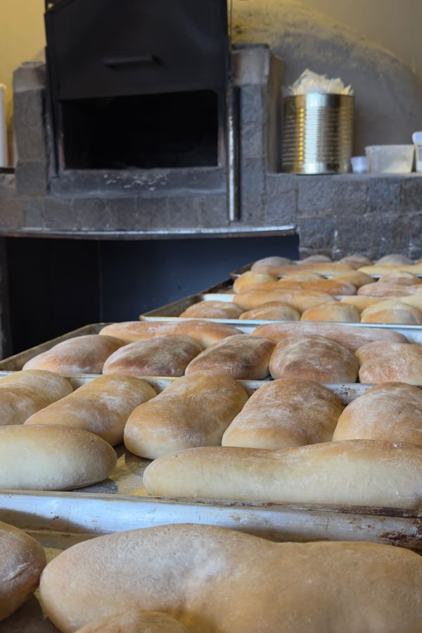 Bandejas con panes caseros para lomos frente al horno de barro