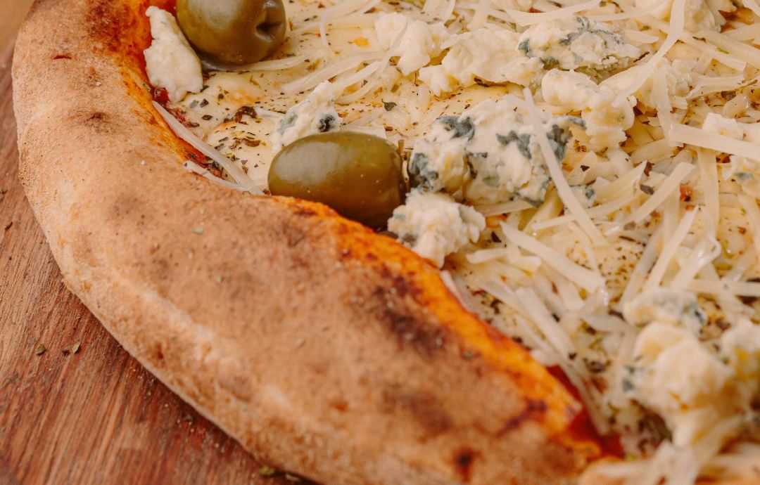 Borde de pizza a la piedra con manchas del horno de barro, queso azul y aceitunas