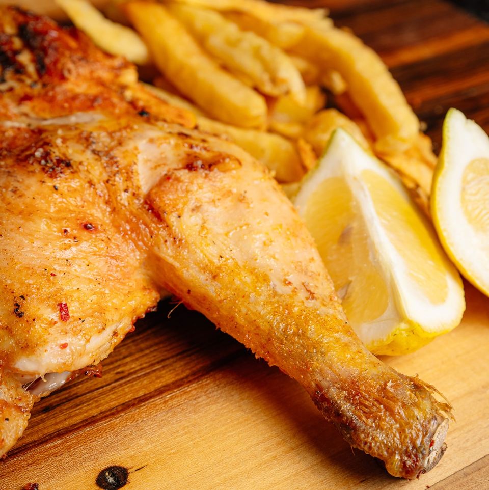 Medio pollo a la leña dorado con papas fritas y limón